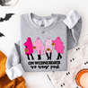 Gray sweatshirt with pink ghost graphics and text on a Halloween-themed background