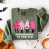 Green sweatshirt with pink ghosts and text on a Halloween-themed background