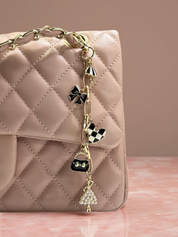 Quilted pink handbag with decorative charm on a pink surface