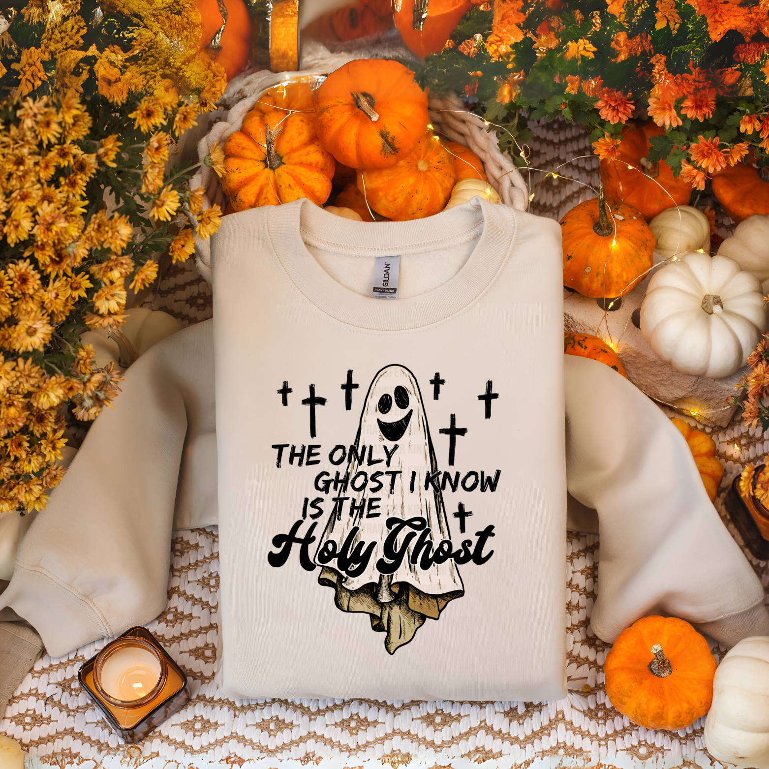 Beige sweatshirt with ghost graphic and text in a Halloween-themed setting with pumpkins and flowers.